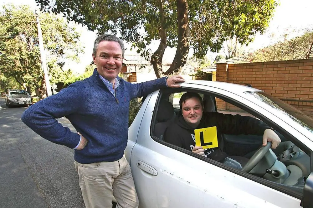 Driving instructor and learner driver beside the lesson car on a local street